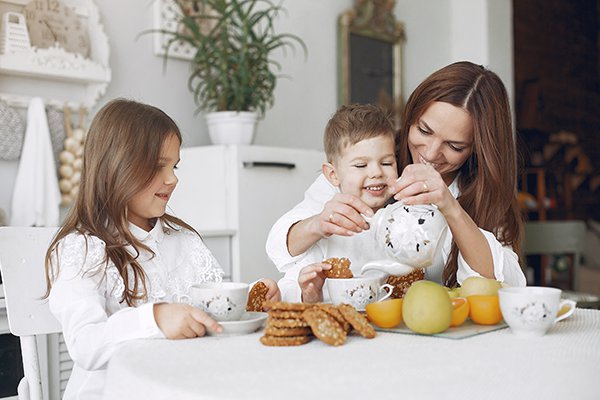 Madre con hijos sentados en la cocina y desayunando - Retos