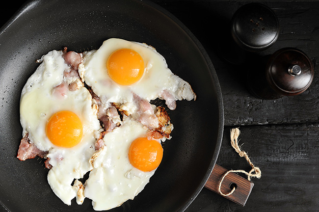 fried-eggs-with-bacon-pan-black-background
