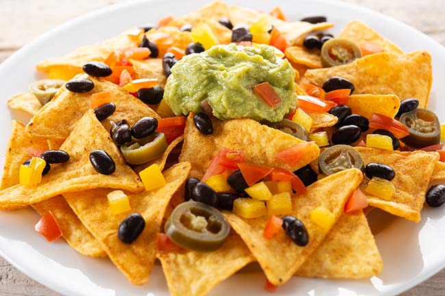 mexican-nachos-tortilla-chips-with-black-beans-guacamole-tomato-jalapeno-wooden-table 