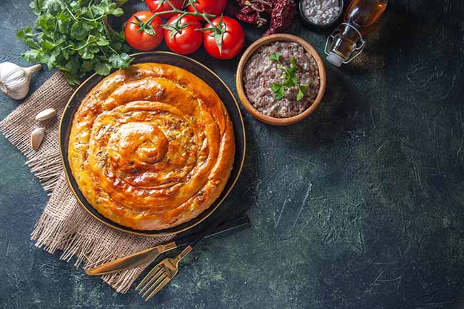 top-view-delicious-meat-pie-with-ingredients-dark-surface
