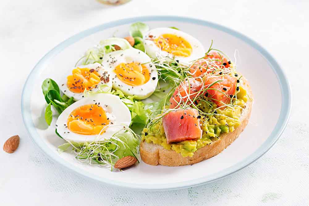 Sándwich-abierto-saludable-sobre-tostadas-con-aguacate-y-salmón-huevos-cocidos-hierbas-semillas-de-chía-con-muchas-proteínas-Retos